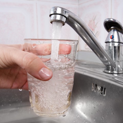 close up view of someone filling a glass up from the sink