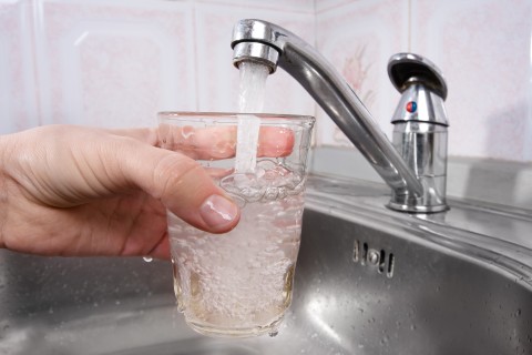 close up view of someone filling a glass up from the sink